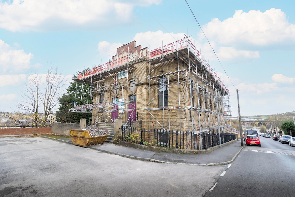 Red Group scaffolding rig at dawn — Bradford terraced site, sky-replacement composition by Status Photography